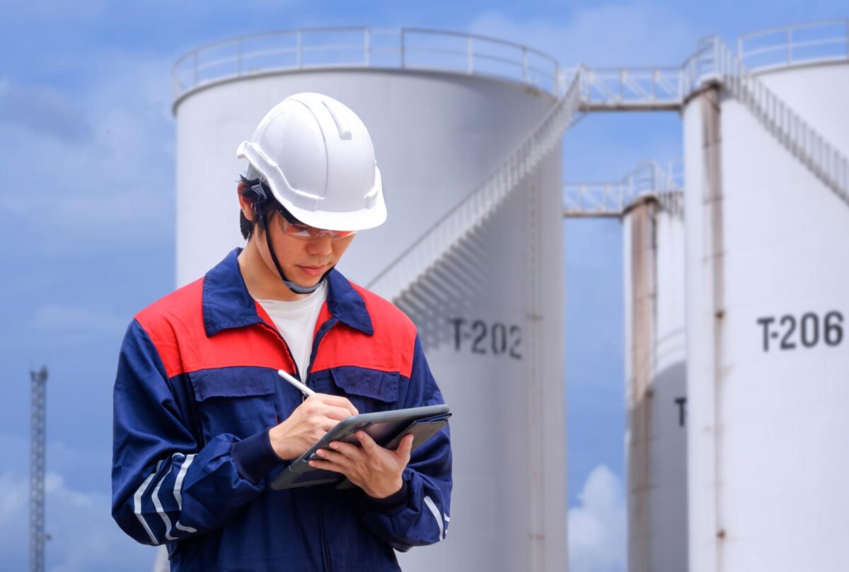 oil and gas engineer at refinery writes on tablet