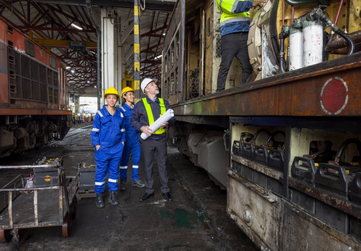 team of workers look on as colleague inspects train