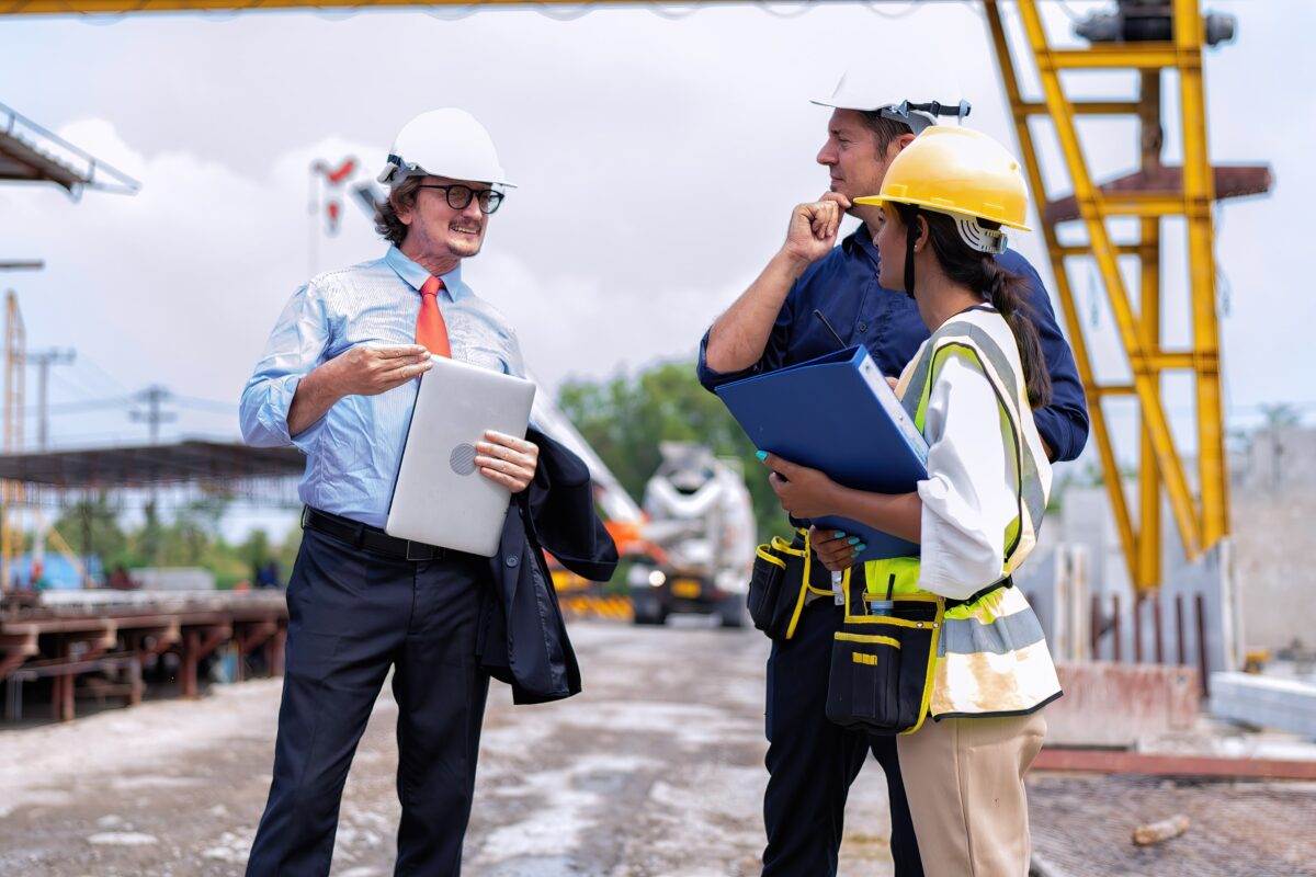 manager in hard hat and office clothes talks to two site workers