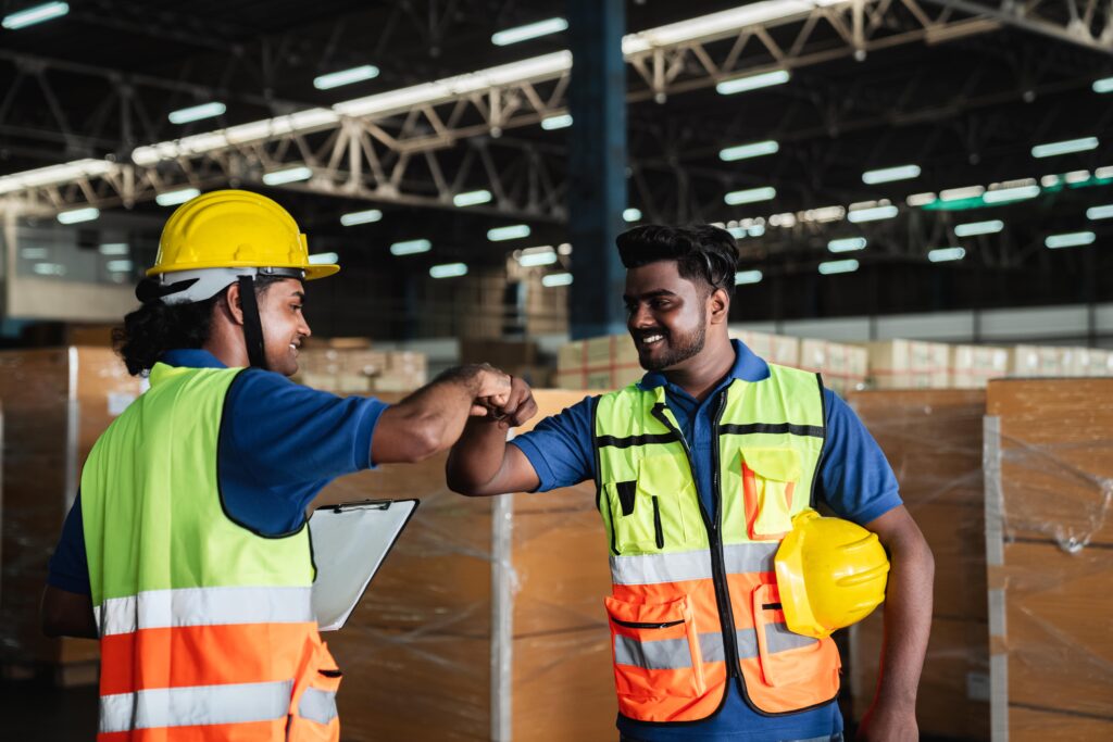 two workers fist bump inside warehouse