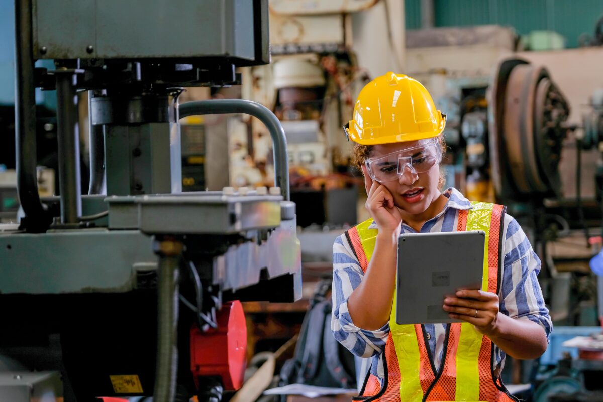 technician standing next to machine looking at tablet