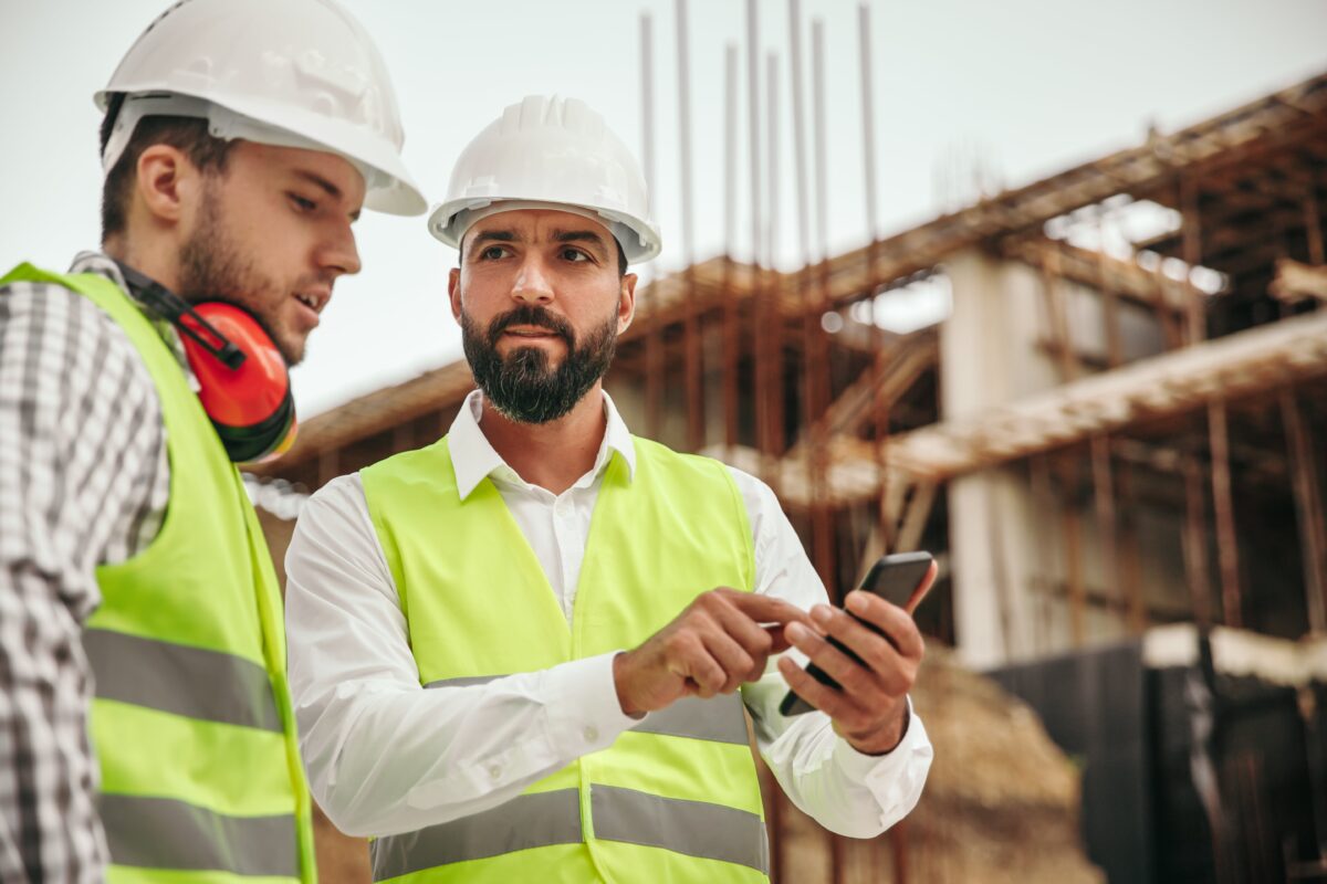two technicians with smartphone at construction site
