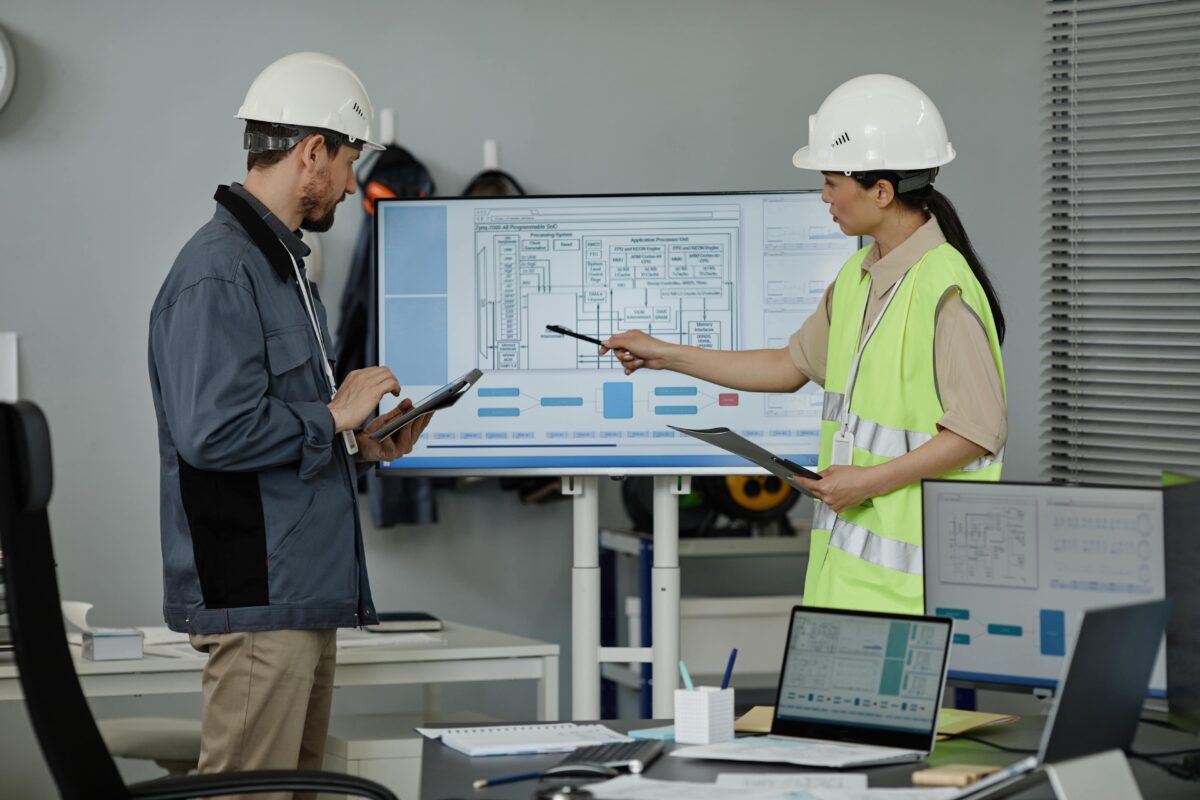 two engineers viewing blue prints on a screen