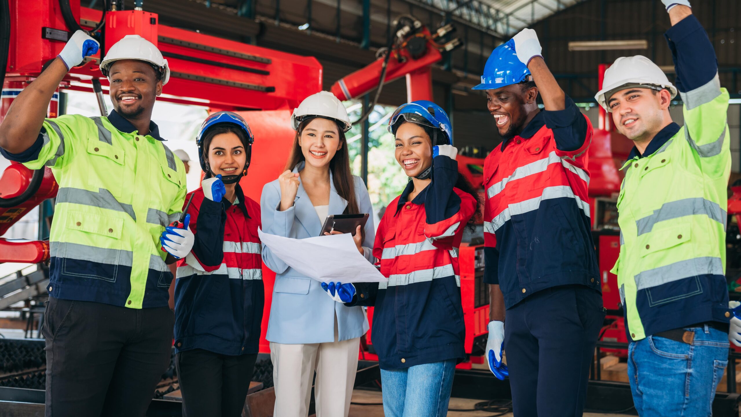 team of workers in work facility smilling and make jubilation signs